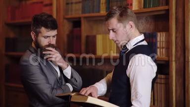 两个人正在图书馆里讨论，手里拿着一本书。 图书馆的科学证据。 概念